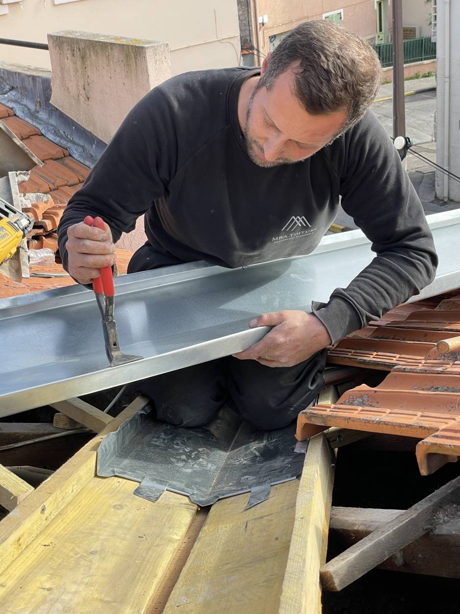 Zingueur façonnant une gouttière en zinc sur le chantier