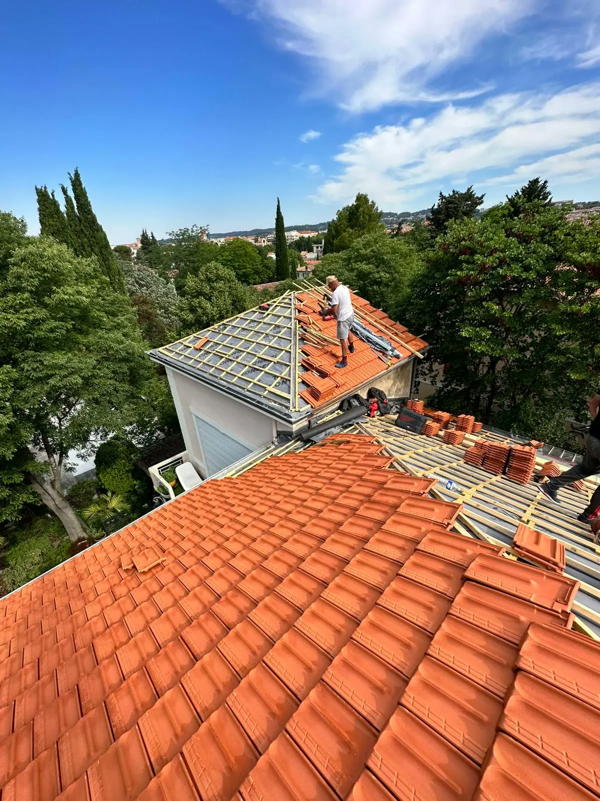 Couvreurs HS Toiture posant des tuiles neuves sur un chantier de rénovation de toiture